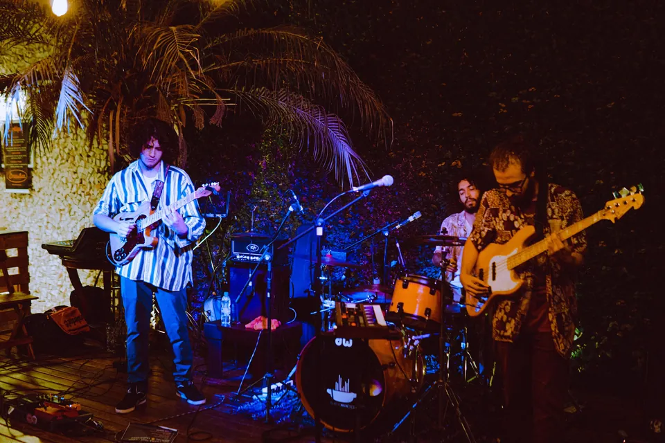 Capybara Trio tocando ao vivo em um palco iluminado.