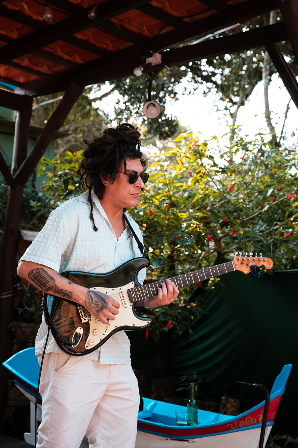 Guitarrista de Los Mudos tocando em um espaço aberto entre árvores.